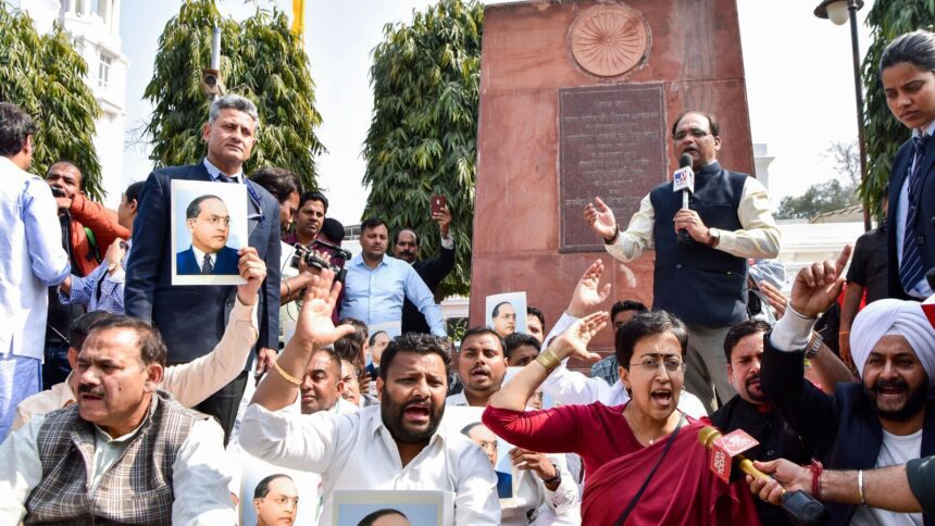 Atishi with AAP MLAs stages a protest outside the Legislative Assembly over removing BR Ambedkar's pictures from Delhi CM's office following her suspension from the Assembly, in New Delhi on Tuesday.