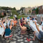 Community members raise their arms during a gratitude poem at a supper in Westbrook, Maine, in July 2025 [Courtesy of Community Plate]