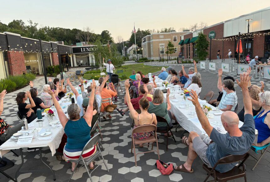 Community members raise their arms during a gratitude poem at a supper in Westbrook, Maine, in July 2025 [Courtesy of Community Plate]